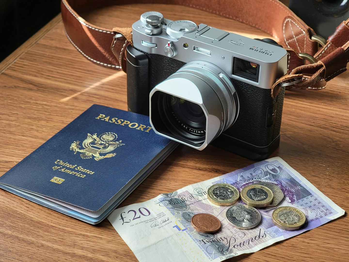Reiseutensilien wie Reisepass, Geld und Kamera auf Holz.