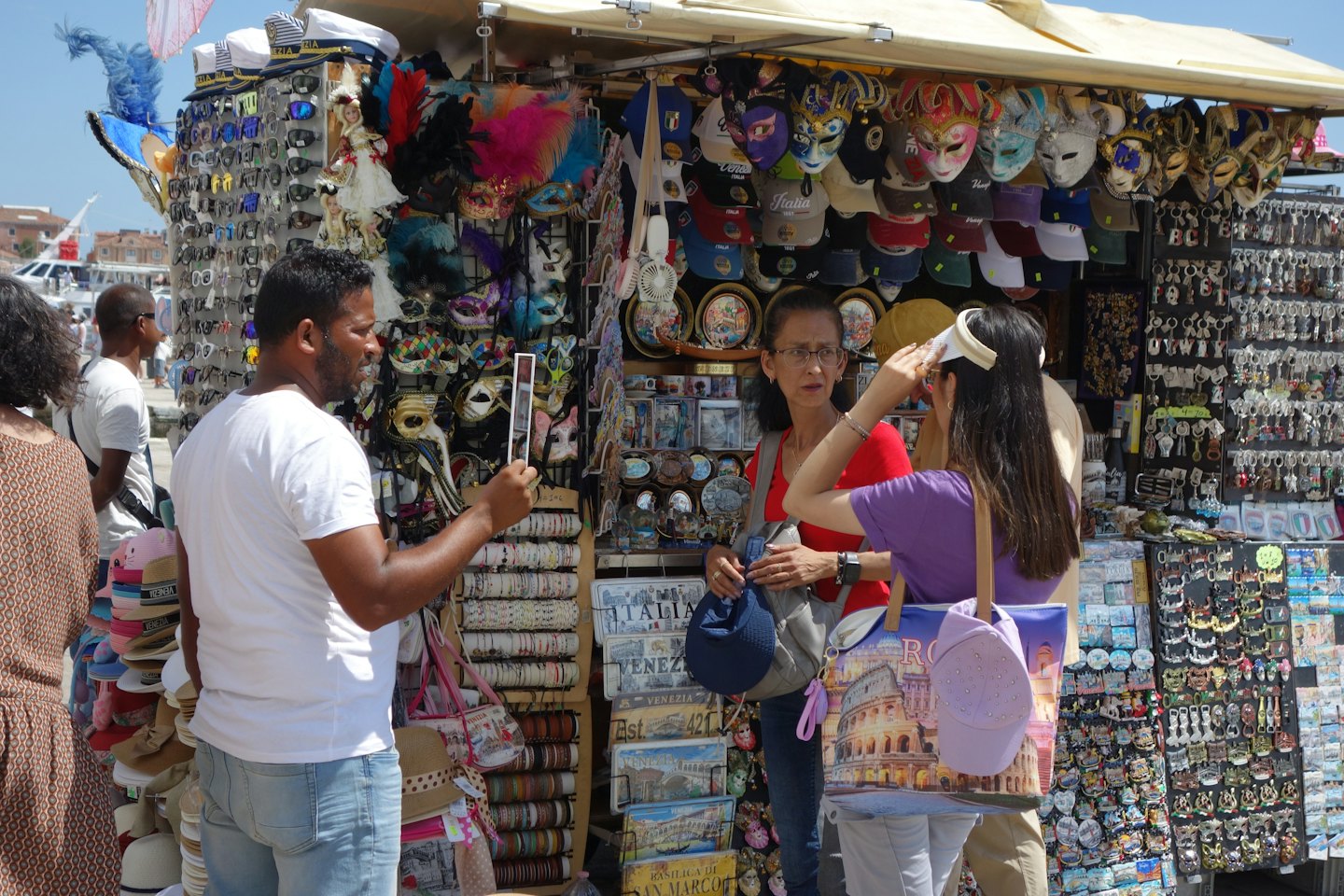 Touristen stöbern an einem Marktstand voller Masken und Souvenirs.