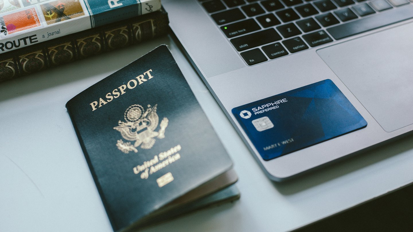 Reisepass, Kreditkarte und Laptop für Reiseplanung.